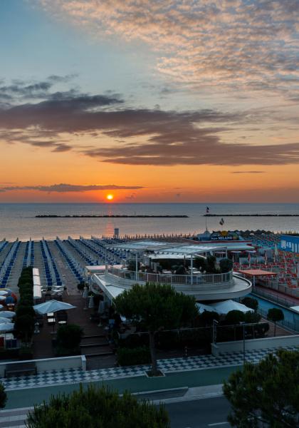 Tramonto su una spiaggia attrezzata con ombrelloni e lettini.