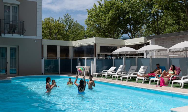 Piscina con persone che giocano e si rilassano.